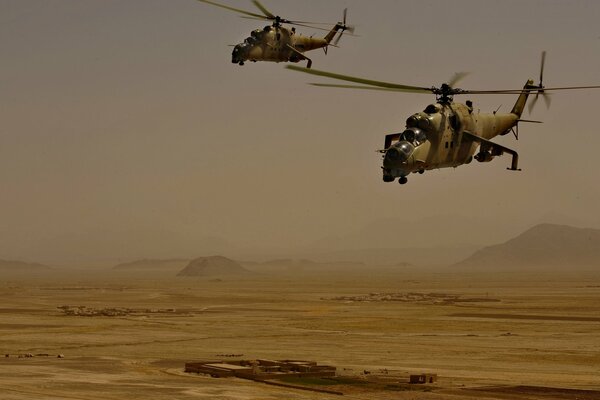 Two shark helicopters are flying through the sultry desert