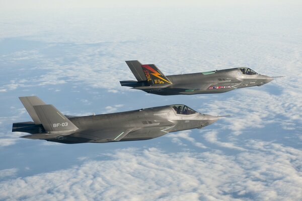 Two F 35 bombers are sailing high above the clouds