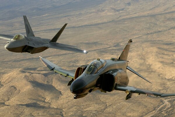 Los poderosos cazas estadounidenses f-22raptor y F-4phantom2 en el cielo contra el fondo de la tierra
