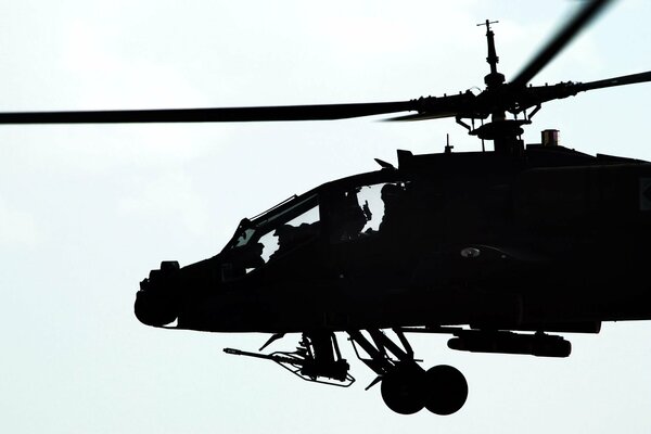 Silhouette eines fliegenden Hubschraubers mit einem Maschinengewehr