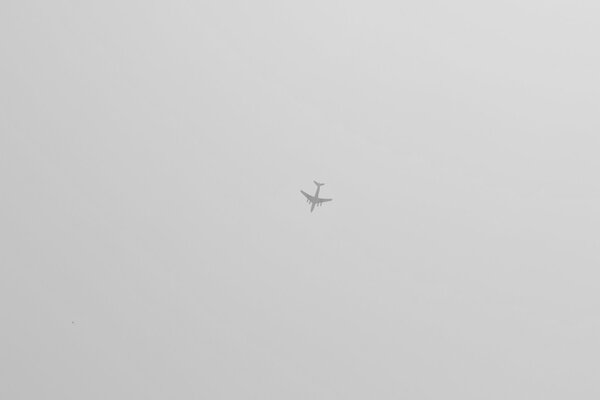 Avión alto en el cielo gris