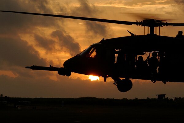 Helicopter taking off against the background of sunset