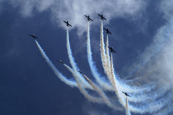 Desfile de aviones con pluma en el cielo