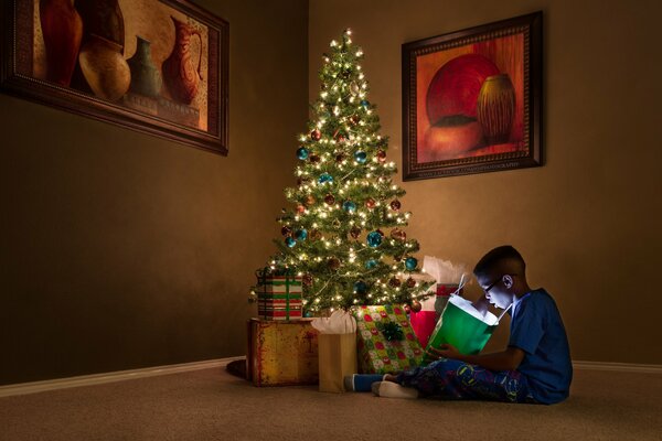 A boy with gifts at the Christmas tree