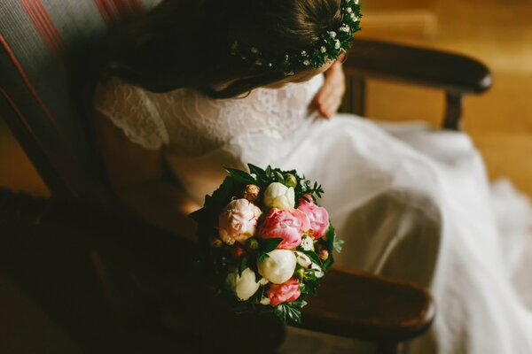 Mariée avec un bouquet de pivoines assis sur une chaise