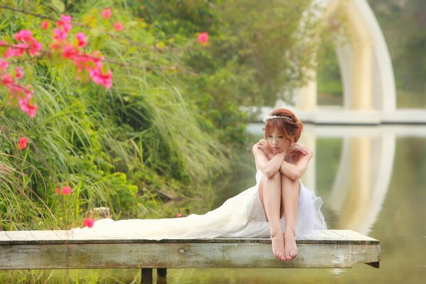 The red-haired bride is sad by the pond