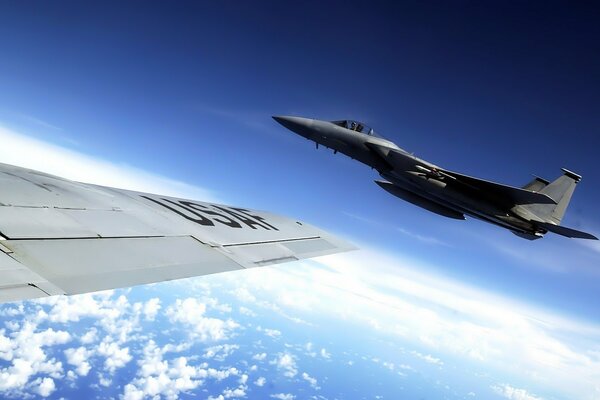 Photo of an airplane flying high in the sky from the wing of another plane