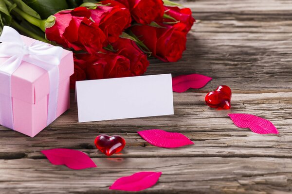 Розовая подарочная коробка с белой лентой и красные розы