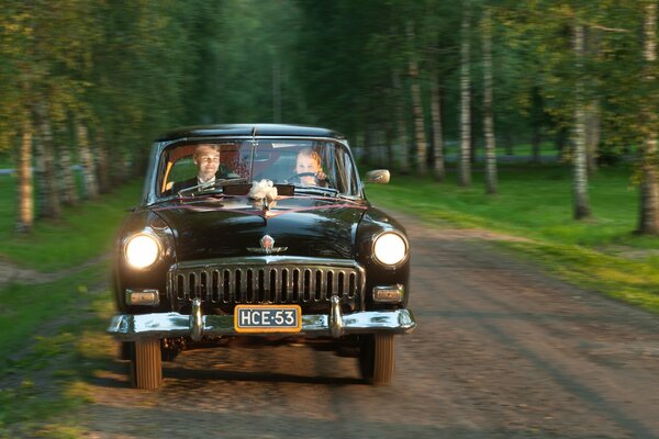 The bride and groom are going to the wedding in a retro car