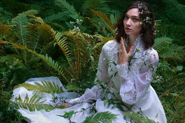 A model in a wedding dress with a fern