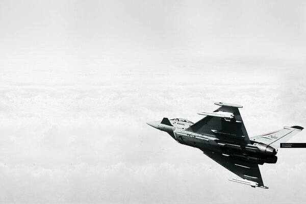 A military plane is flying in the clouds