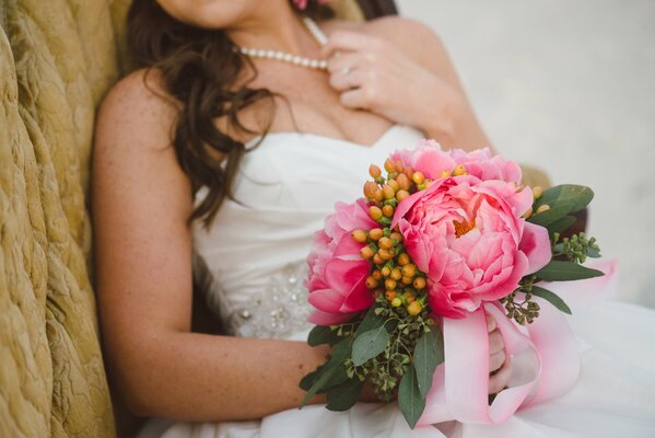 La novia sostiene un ramo de peonías en sus manos