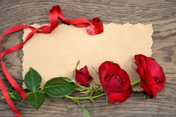 Red roses, parchment and a red ribbon with a medallion in the shape of a heart