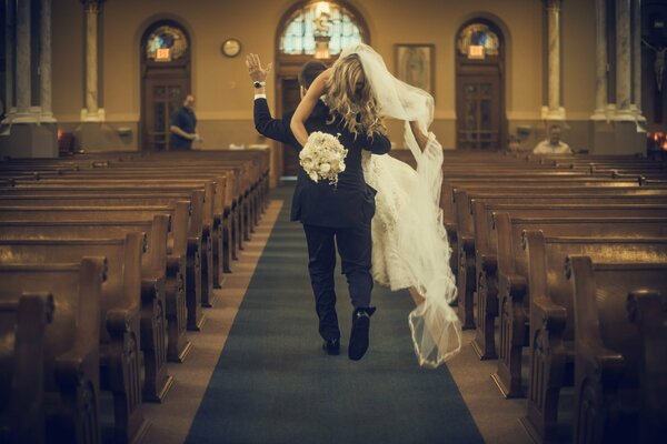 Der Bräutigam trägt die Braut durch die Kirche