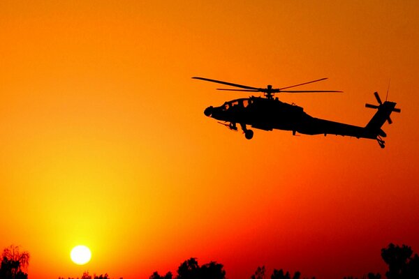 Silhouette of a helicopter taking off at sunset