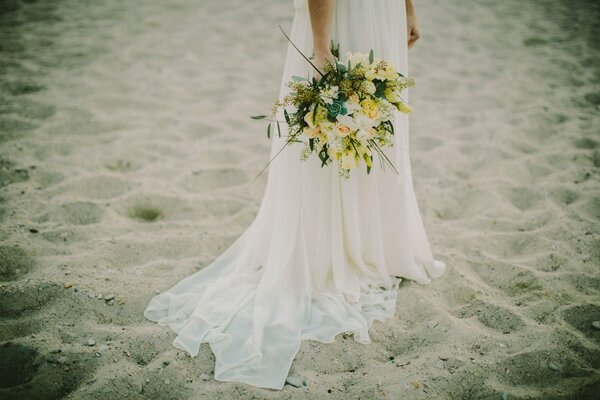 Sposa con bouquet luminoso sulla spiaggia