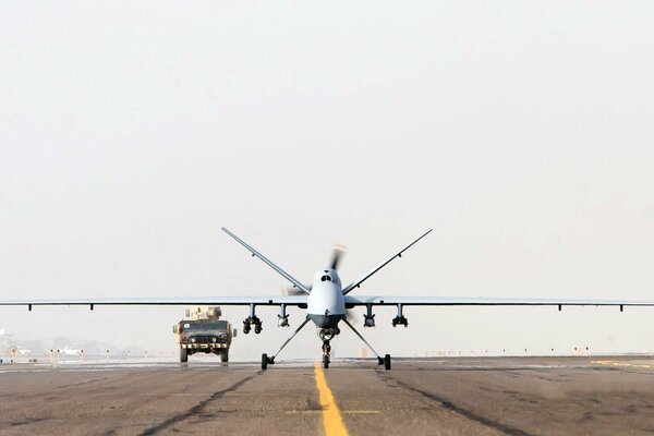 Un potente Dron en la pista acompañado de un vehículo militar
