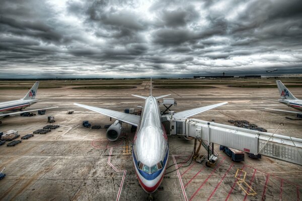 There are several passenger planes at the airfield against a cloudy sky