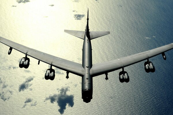 A large plane flies over clouds and water