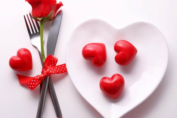 Ein Teller mit Herzen und einer Rose auf dem Tisch