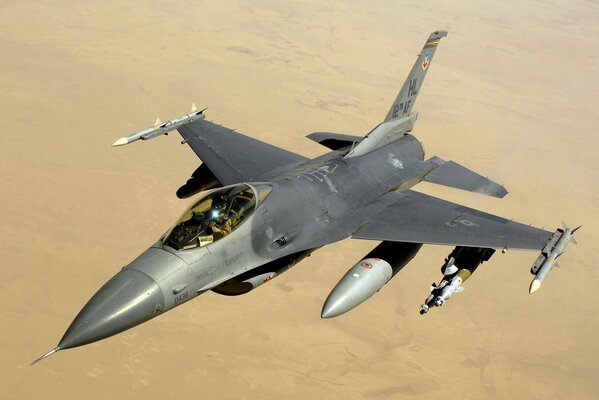 The f-16 is flying through the sky over the desert