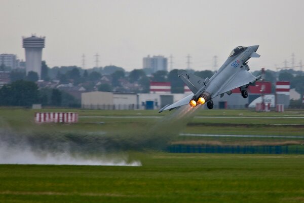 A fighter jet takes off from the airport leaving a trail