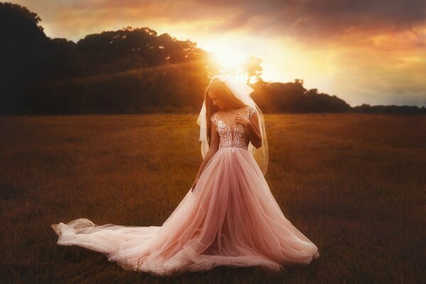 A girl in a bride s dress is standing in a field