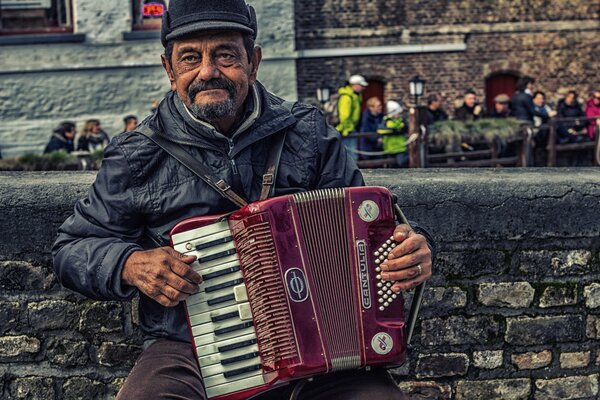 An elderly man plays a red accordion