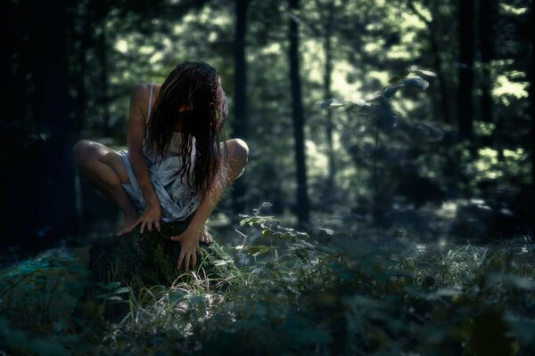 Raccapricciante ragazza della foresta seduta su un moncone immagine di Halloween