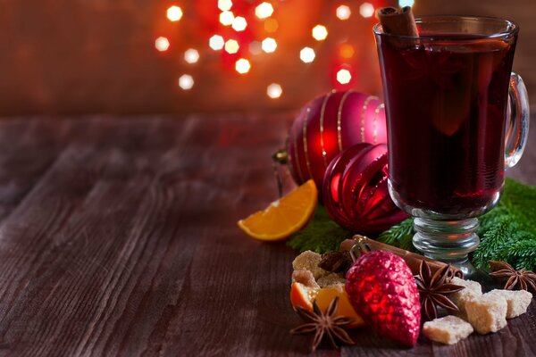 Taza de vino caliente en la mesa con especias y juguetes de Navidad