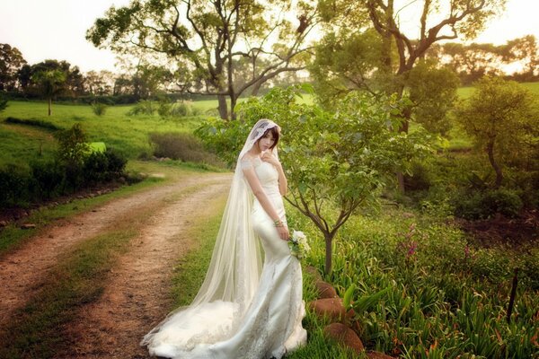 A girl in a wedding dress on the road in the forest