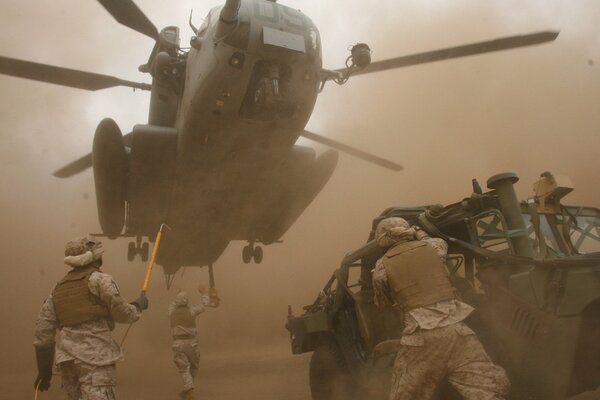 A combat jeep is brought to a cargo helicopter