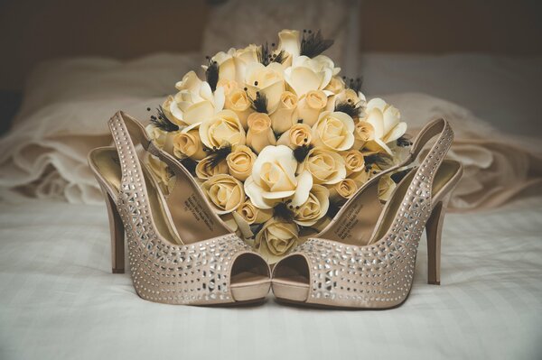 Bouquet de roses sur le lit et une paire de belles chaussures