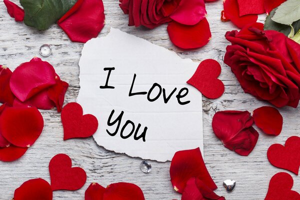 The inscription I love you among red hearts and rose petals