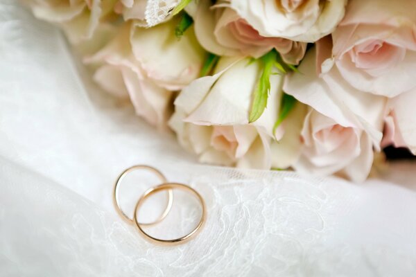 Wedding rings next to white roses