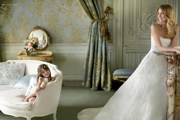 Happy mother and daughter in a wedding photo shoot in white dresses among the aristocratic decorations of the room