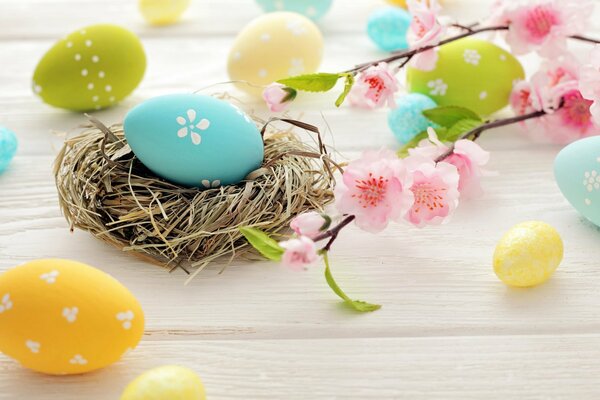 Huevo de Pascua en una cesta. Hermosas flores. Huevos de colores en la mesa