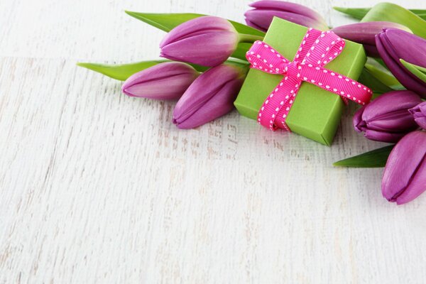 A gift and purple tulips on the table