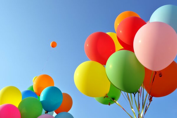 Dos paquetes de globos de vacaciones multicolores contra el cielo azul y una bola en la distancia