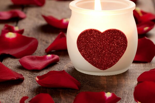 Candle with a heart among rose petals