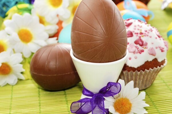 Chocolate eggs and cake on the background of daisies