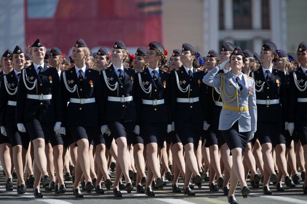 Military girls are marching on Red Square. Red Square is crowded on Victory Day