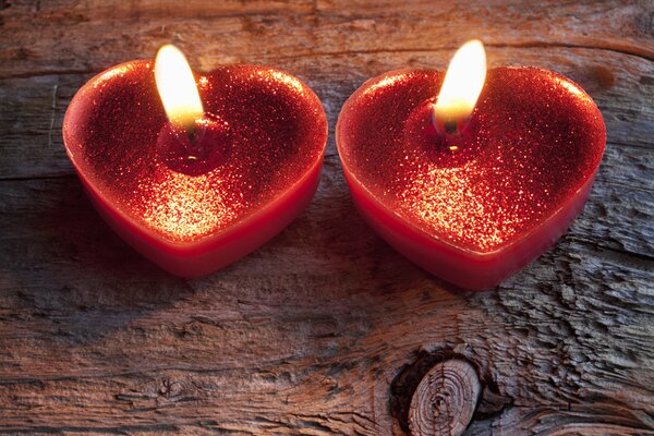 Two red heart-shaped candles are burning