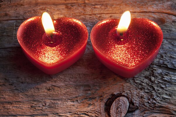 Dos velas rojas en forma de corazón se queman