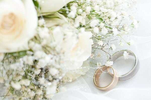 Dos anillos de boda en la tela al lado del ramo