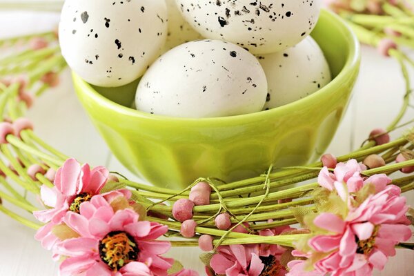 Huevos de Pascua de mármol en un tazón de ensalada contra una corona de flores Rosadas