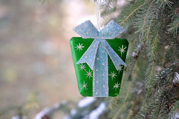 Un pequeño regalo en un paquete verde que cuelga en el árbol de Navidad