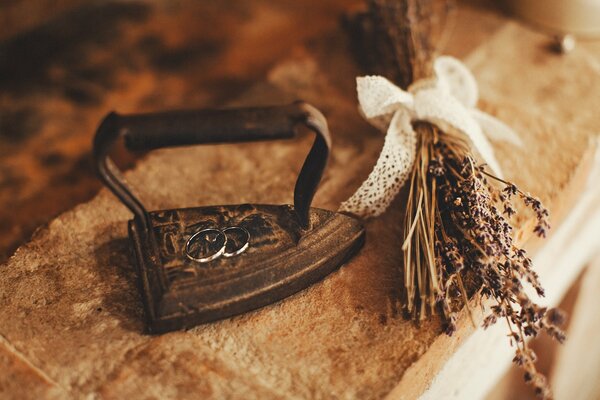 An antique iron with two wedding rings on it