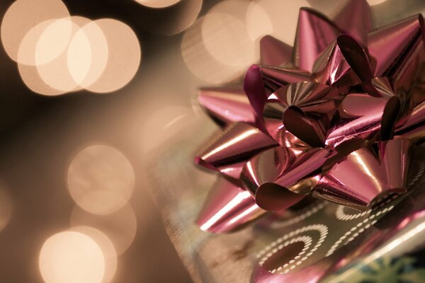 Cadeau sur un fond d or avec un arc brillant rose