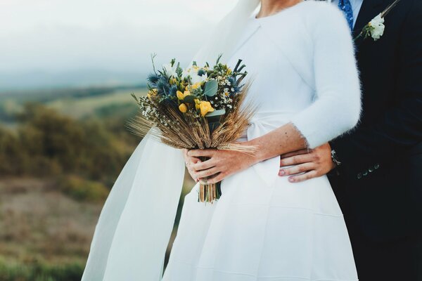 Sposi e bouquet da sposa in mano